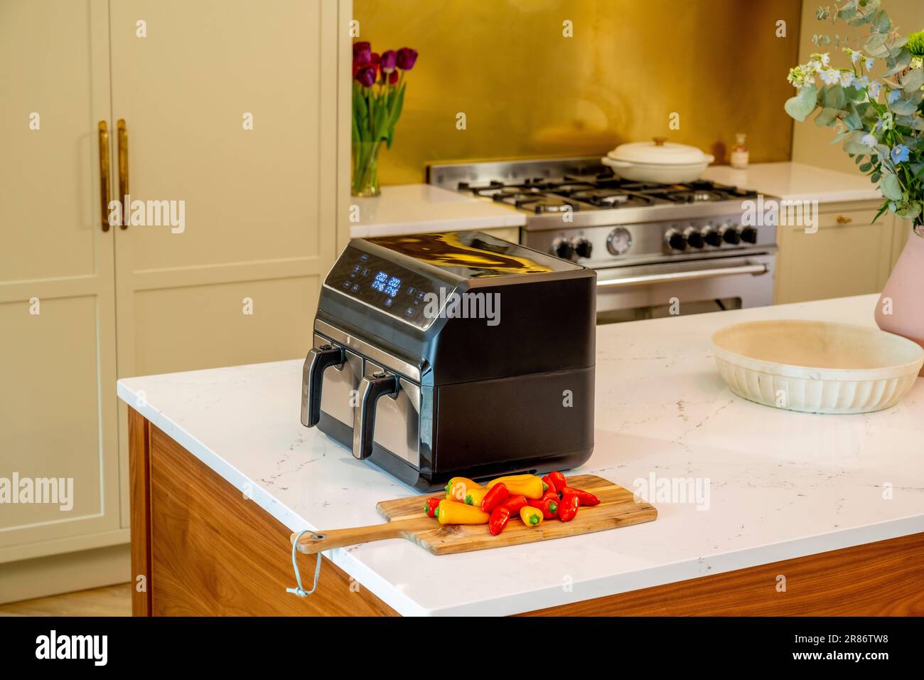 Airfryer sur le plan de travail en marbre de l'îlot de cuisine domestique avec une cuisinière à gaz traditionnelle en arrière-plan. Banque D'Images