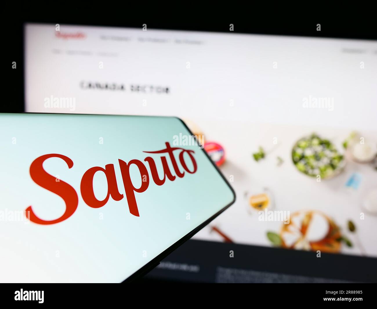 Smartphone avec logo de la société laitière canadienne Saputo Inc. À l'écran devant le site Web des affaires. Concentrez-vous sur le centre de l'écran du téléphone. Banque D'Images