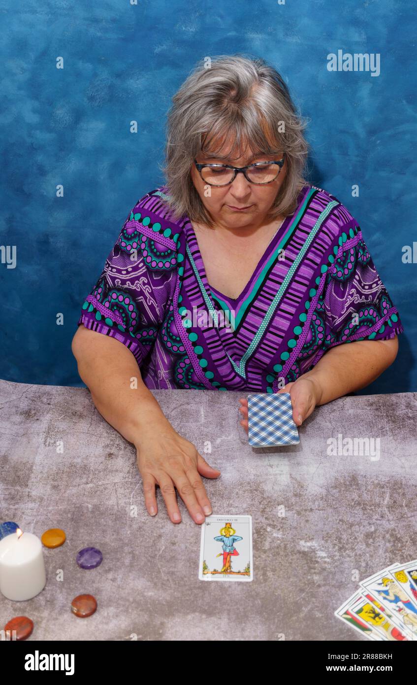Une femme plus âgée à cheveux blancs, sans pythoness, qui jette des cartes de tarot Banque D'Images