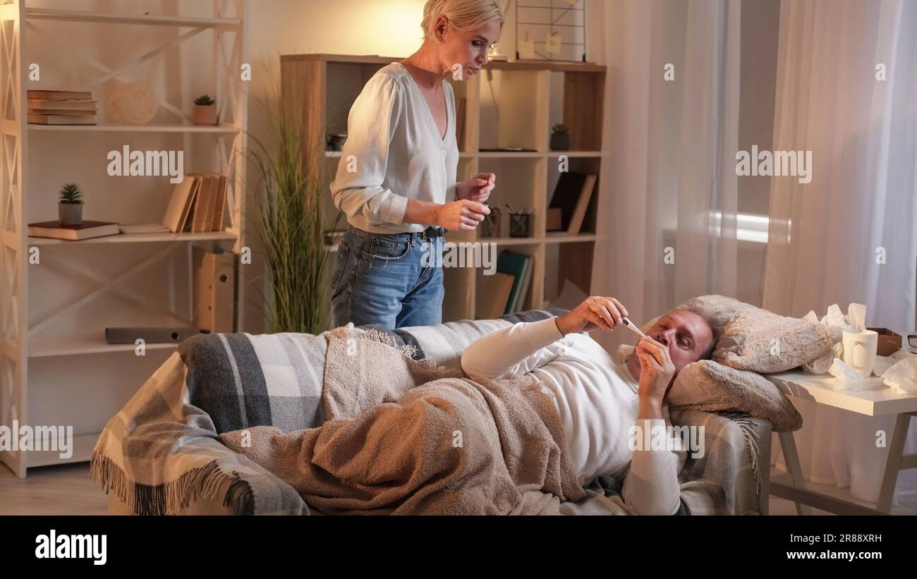 Soutien à la fièvre grippe mari femme prenant de la température Banque D'Images