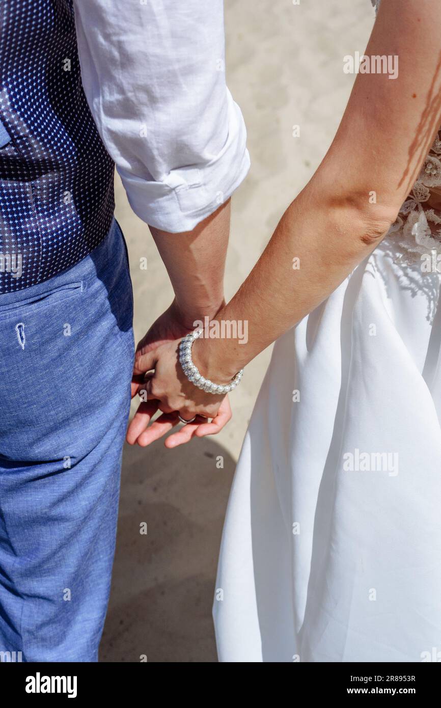 La main dans la main mariée et marié, assis dans un désert dans le suset Banque D'Images