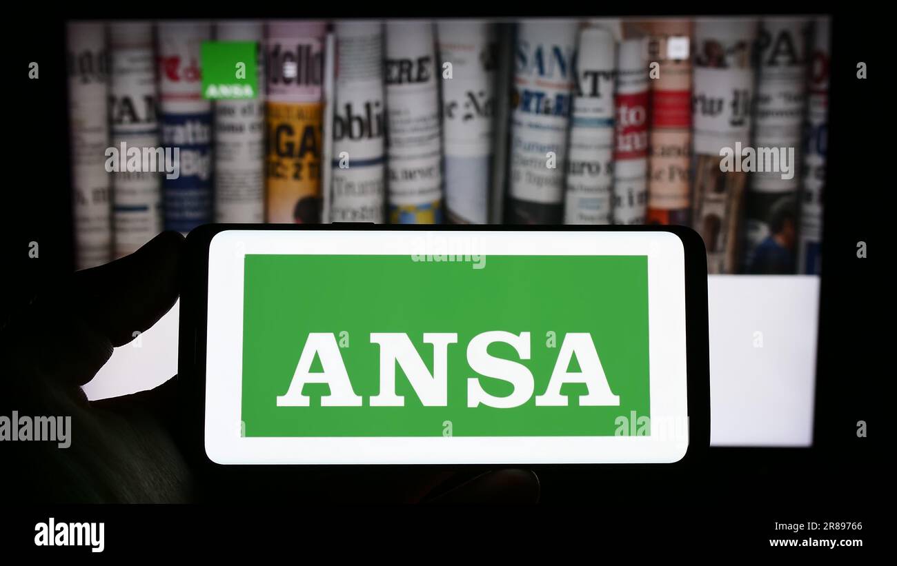 Personne tenant un smartphone avec le logo de l'Agence Nazionale Stampa Associata (ANSA) à l'écran devant le site. Mise au point sur l'affichage du téléphone. Banque D'Images
