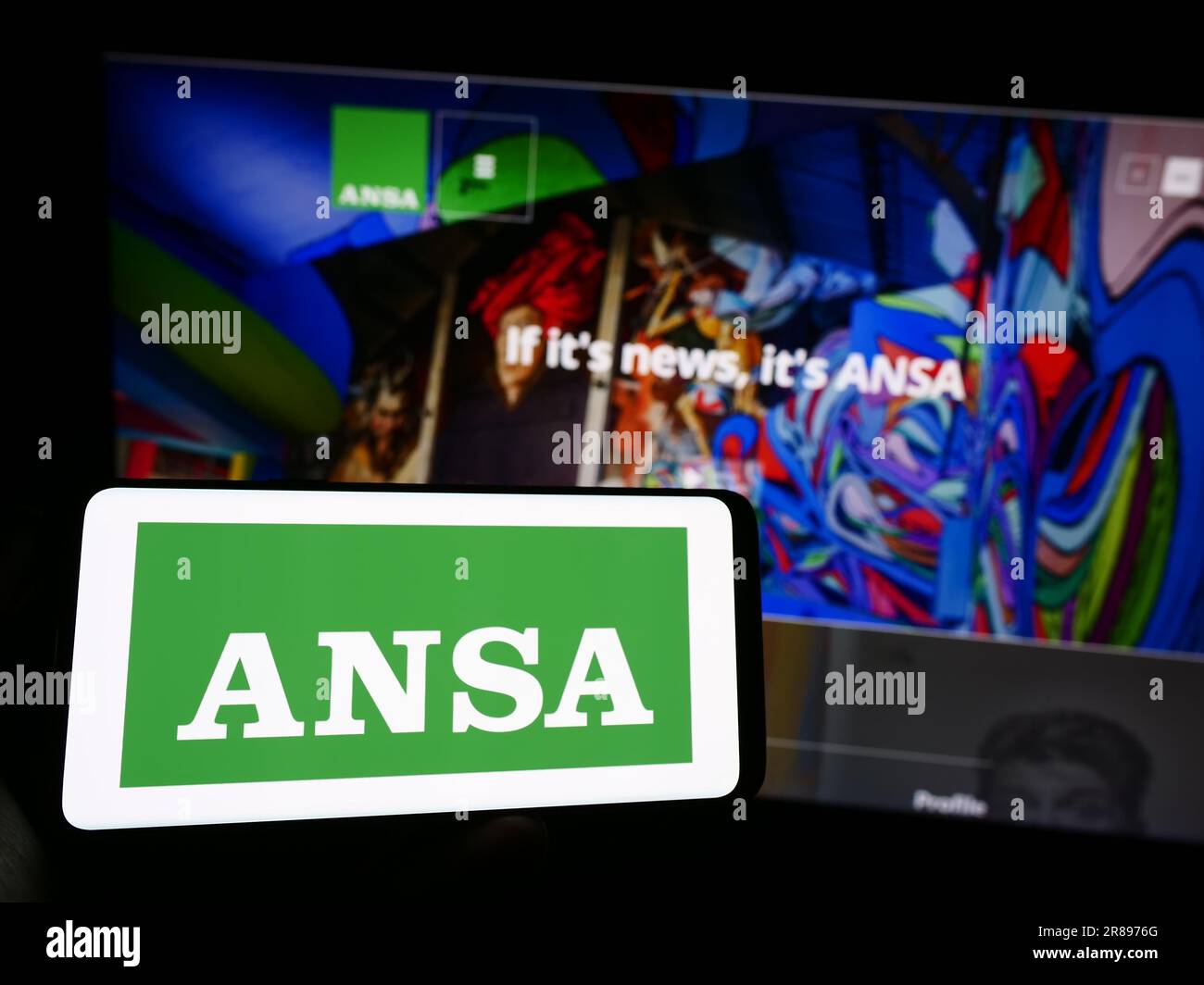 Personne tenant un téléphone portable avec le logo de l'Agence Nazionale Stampa Associata (ANSA) à l'écran en face de la page web. Mise au point sur l'affichage du téléphone. Banque D'Images