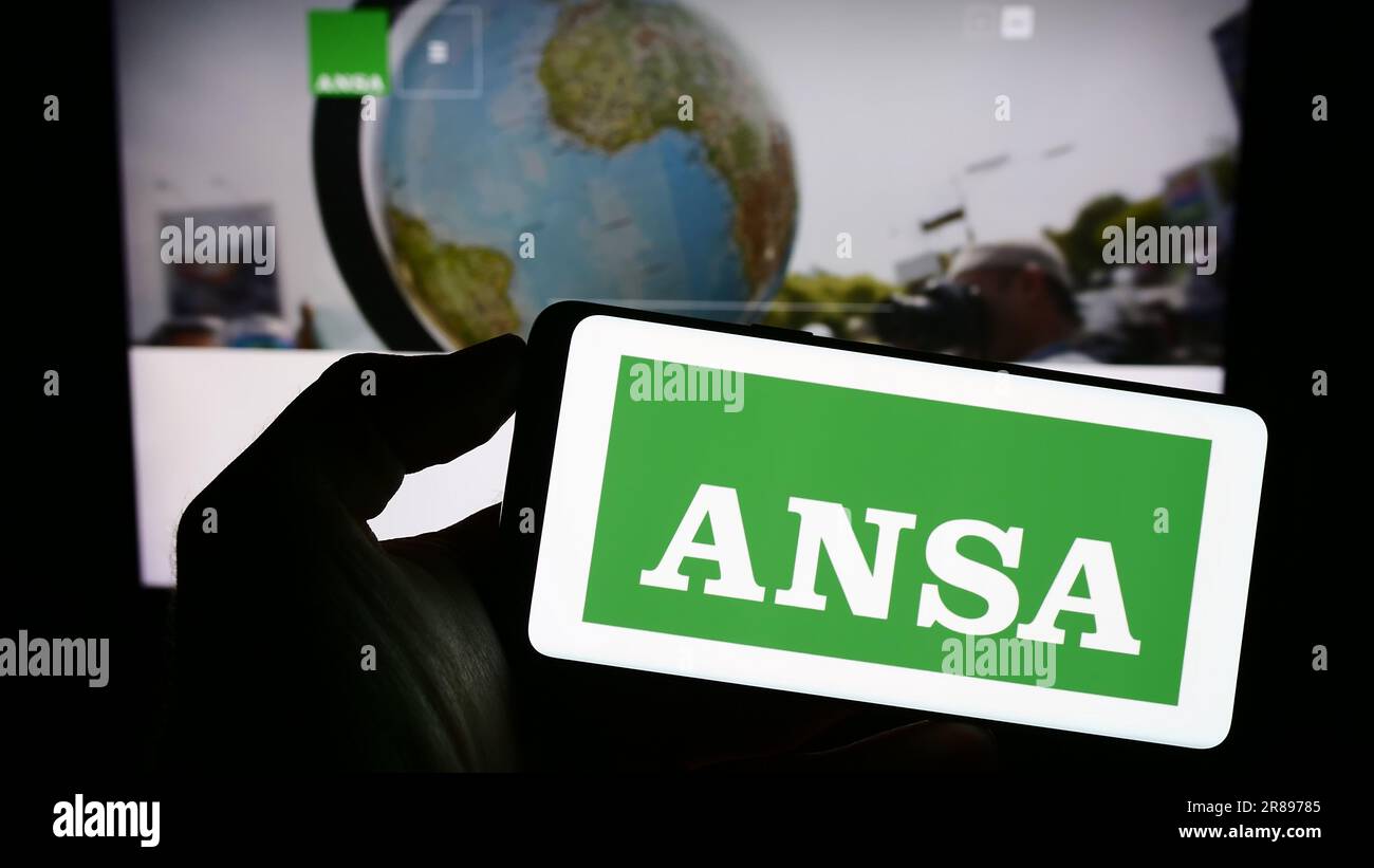 Personne tenant un téléphone portable avec le logo de l'Agence Nazionale Stampa Associata (ANSA) à l'écran en face de la page web. Mise au point sur l'affichage du téléphone. Banque D'Images