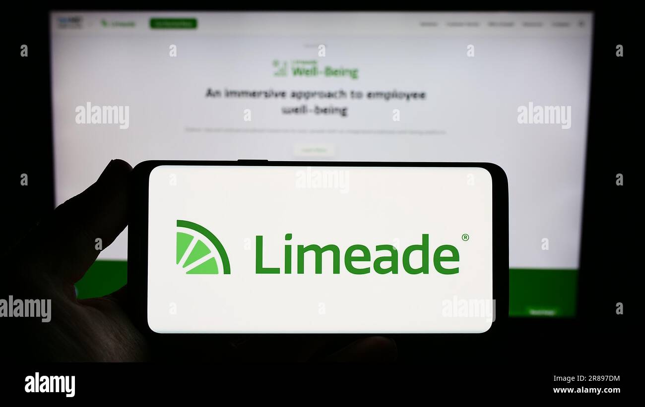 Personne tenant un smartphone avec le logo de l'entreprise américaine de bien-être Limeade Inc. À l'écran devant le site Web. Mise au point sur l'affichage du téléphone. Banque D'Images