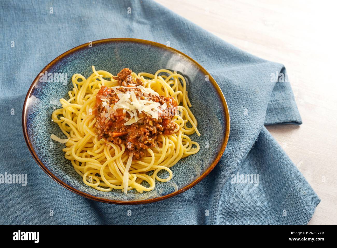 Spaghetti bolognaise, pâtes avec sauce à base de viande hachée et de tomates, garni de parmesan sur une assiette bleue et une serviette, plat de style italien, Copy spa Banque D'Images