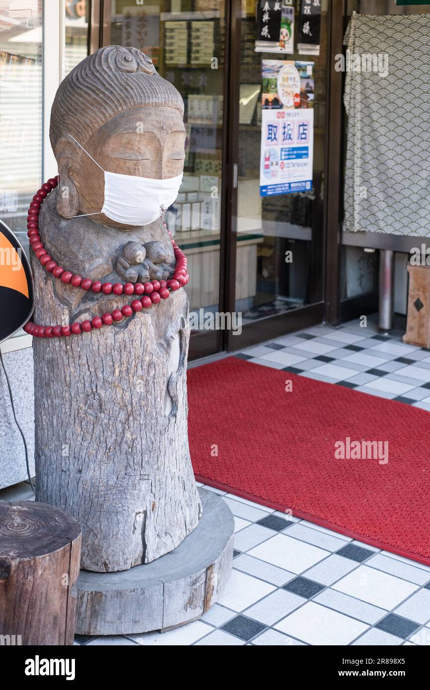 Statue de femme en bois sculpté portant un masque facial et des perles rouges à l'entrée d'une boutique de Koyasan, au Japon. Banque D'Images