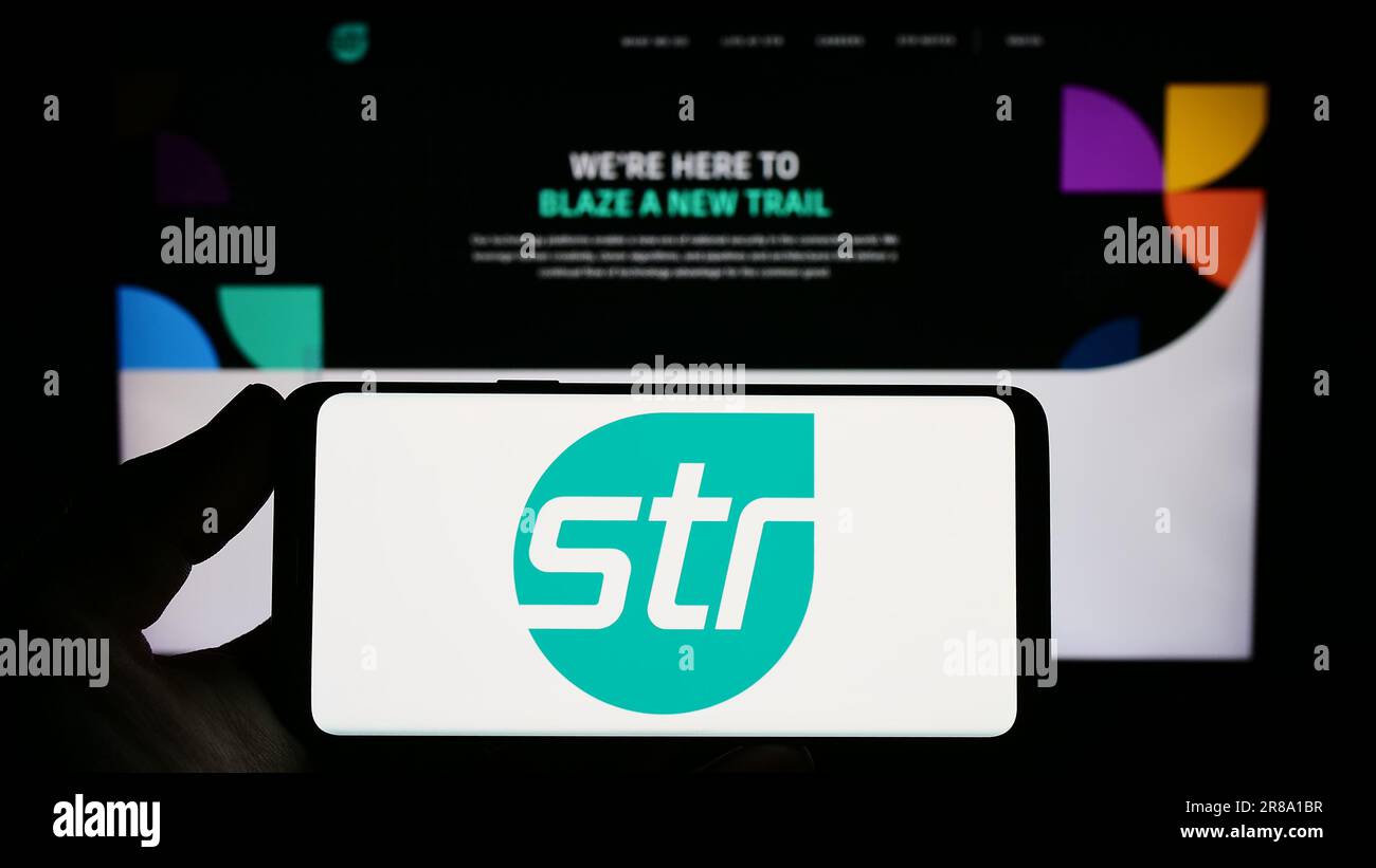 Personne tenant un smartphone avec le logo de Systems and Technology Research LLC (STR) à l'écran devant le site Web. Mise au point sur l'affichage du téléphone. Banque D'Images