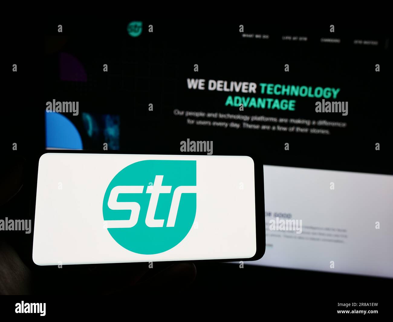 Personne tenant un téléphone portable avec le logo de Systems and Technology Research LLC (STR) à l'écran en face de la page Web. Mise au point sur l'affichage du téléphone. Banque D'Images