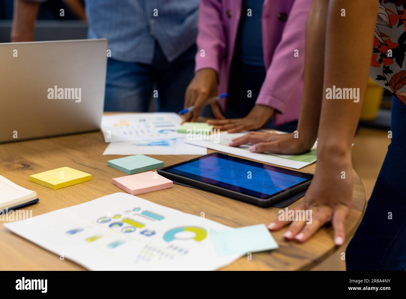 Milieu de divers collègues dans la discussion utilisant tablette et ordinateur portable dans une réunion de bureau occasionnelle Banque D'Images