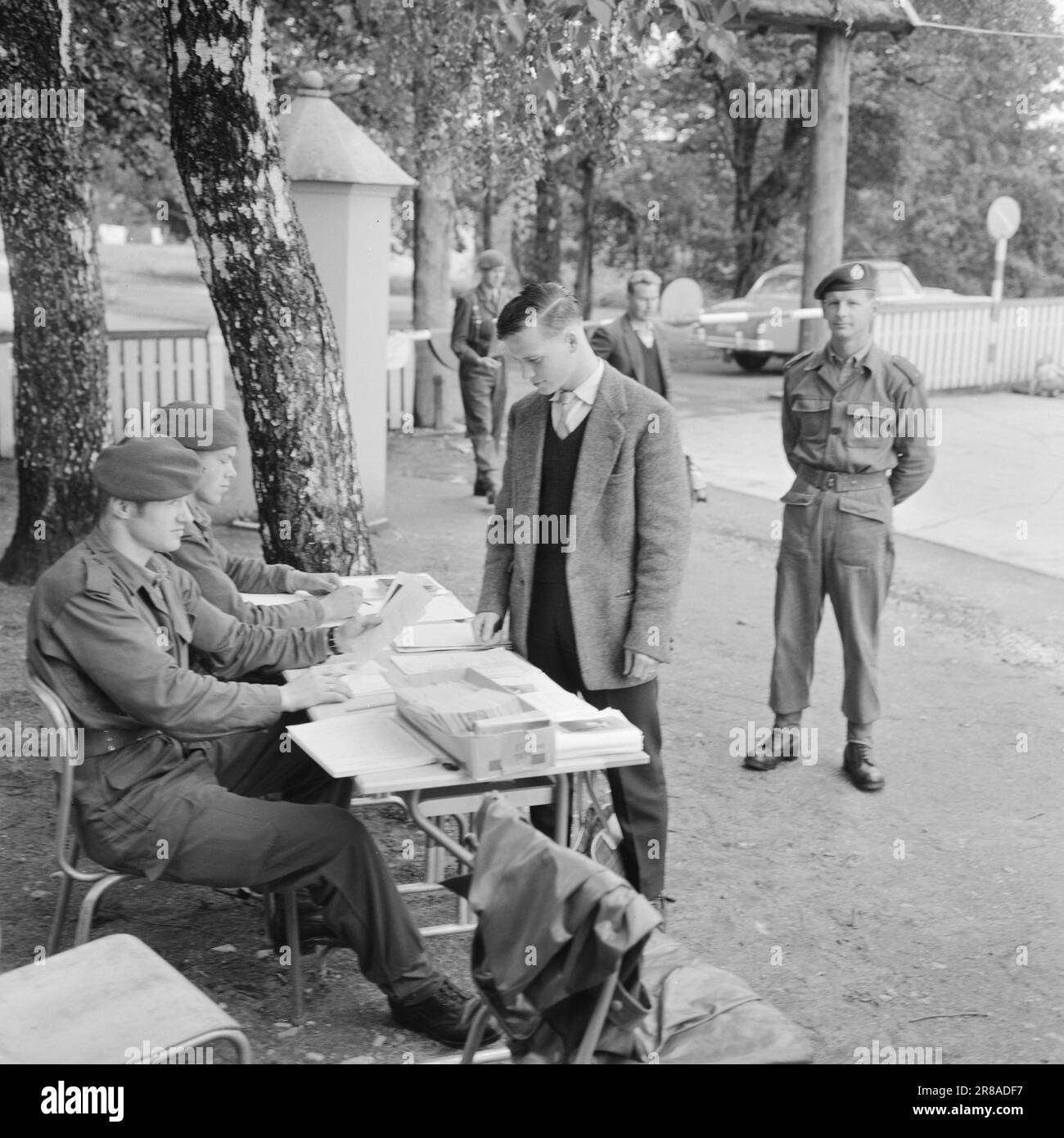 Actuel 32-1-1960: Thore devient une recrue devenir une recrue est une affaire sérieuse. Les sergents, les enseignes, les lieutenants et les capitaines prennent la relève des mères, des pères, des épouses et des fiancees - pendant 16 mois, de longs mois pour un homme de 20 ans. Derrière la barrière Thore Holth se trouve à l'intérieur de la porte du camp. Les papiers sont dans l'ordre et en quelques secondes il est suivi à la caserne par un sergent. « Bienvenue à Lahaugmoen », a déclaré Ensign Thorbjørn Hvattum, qui a montré aux nouveaux arrivants leur chemin dans de nouveaux environnements. Photo: Aage Storløkken / Aktuell / NTB ***PHOTO NON TRAITÉE*** Banque D'Images