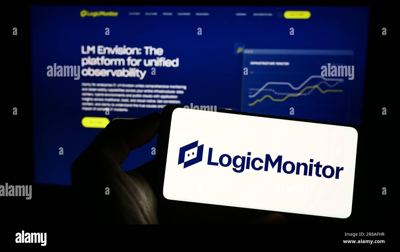 Personne tenant un téléphone portable avec le logo de la société de surveillance américaine LogicMonitor Inc. À l'écran devant la page Web d'affaires. Mise au point sur l'affichage du téléphone. Banque D'Images