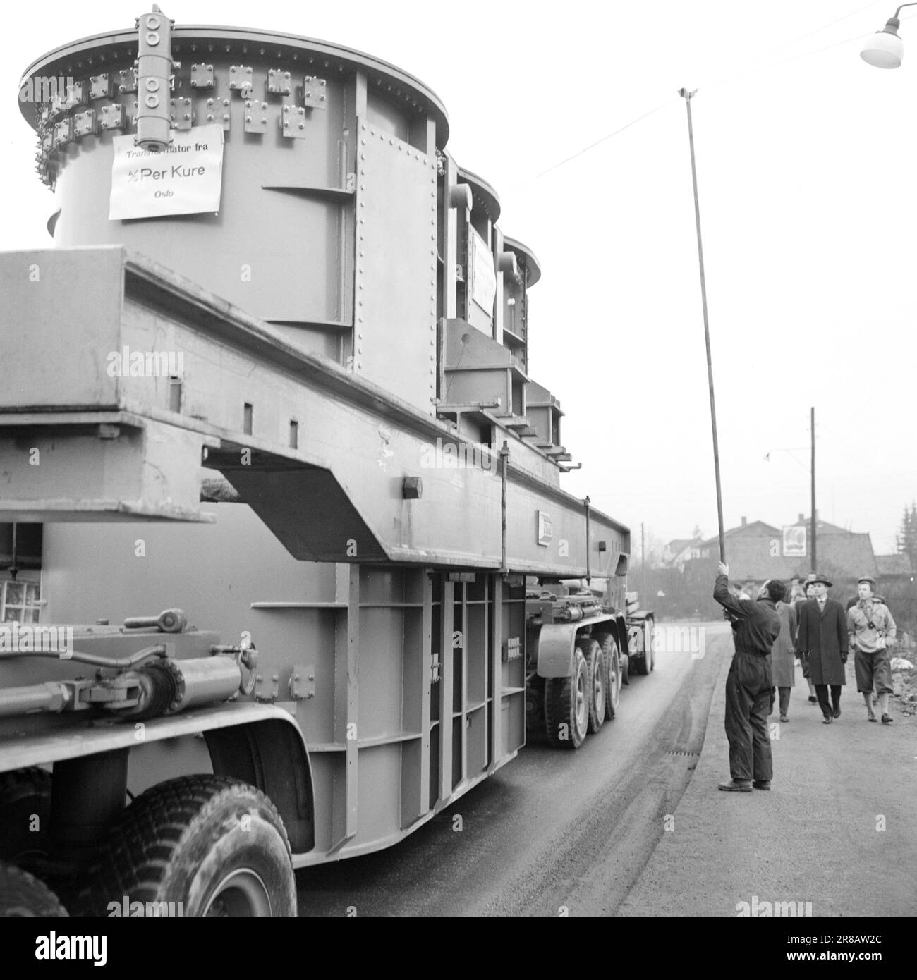 Courant 57-3-1960: Géant sur la visite de la ville quarante roues roulées à l'unisson de Hasle à Ulven à Oslo l'autre jour. Ils ont réalisé un travail historique : le plus grand transformateur norvégien à ce jour, un géant de 205 tonnes, a été transporté de Per Kure A/S vers le site de la société d'éclairage d'Ulven, où il contribuera à l'alimentation électrique. Le transformateur, qui produit 161 000 kilovoltampères, mesure 9,6 mètres de long et 5,7 mètres de large. Oslo Lysverker avait appelé à des renforts pour les grands transports et pas moins de deux chauffeurs étaient en activité. Ils ont reçu leurs commandes de conduite de la virgule Banque D'Images