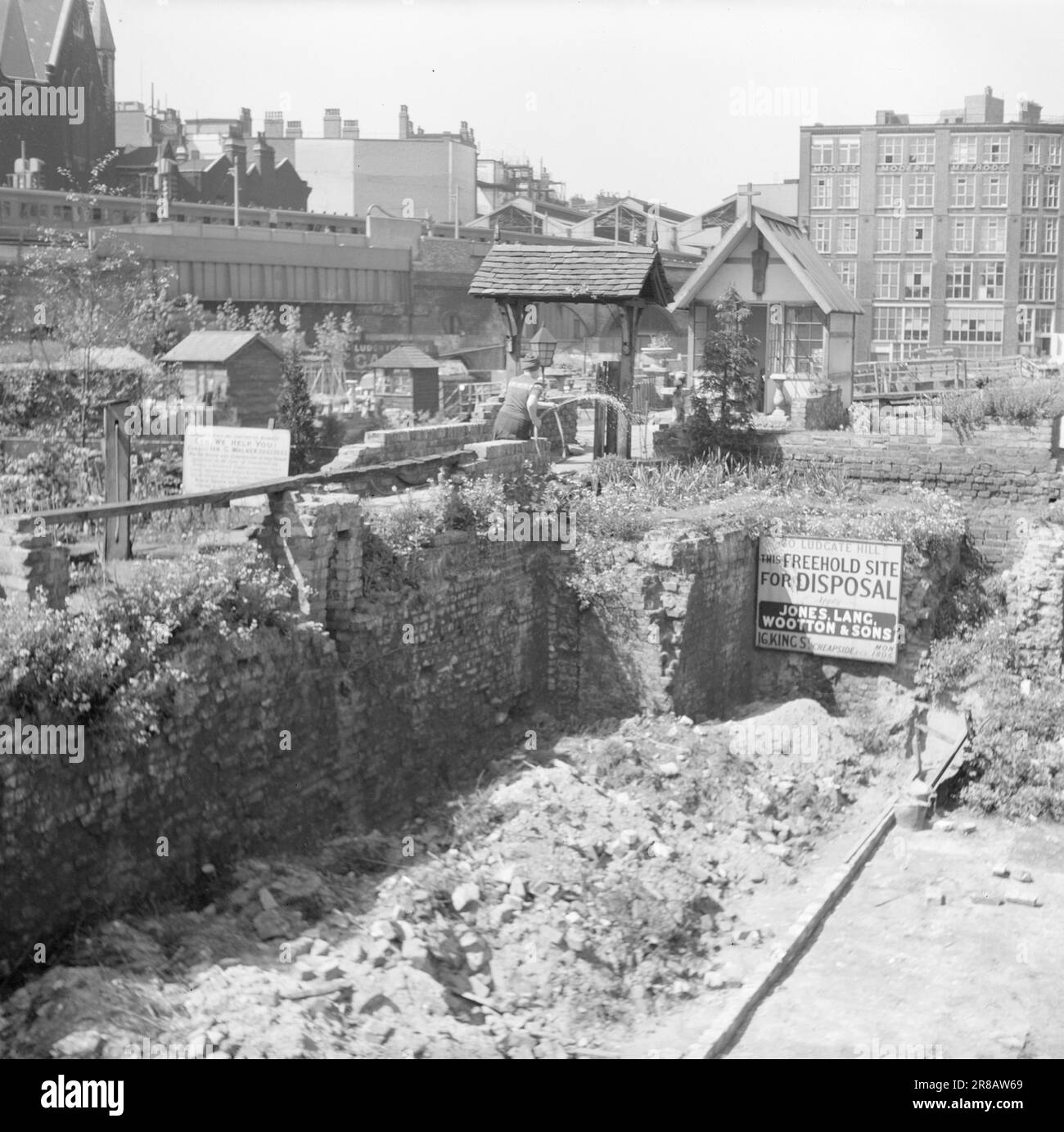 Effectif 12-1951: Rencontre avec LondonEditor Per Bratland lors d'un voyage de reportage à Londres pour couvrir le 'Festival de Grande-Bretagne' avec une représentation du Londres d'aujourd'hui. -Une petite chapelle avec un beau jardin équilibré sur le dessus d'un mur, nous avons trouvé dans ces environs. Un pont avait été construit à partir de la rue, mais il n'était pas ouvert à cette époque de la journée. Au lieu de cela, une dame âgée, probablement bénévole de la congrégation, a arrosé le jardin. Ensuite, la dame buvait du thé, mais elle ne laisserait aucun photographe sur un sol sacré. Le tracé à côté est toujours vacant. - comme indiqué dans l'affiche. Banque D'Images