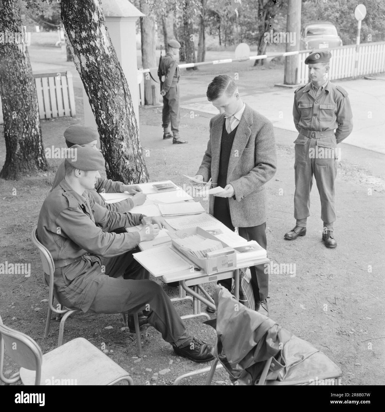 Actuel 32-1-1960: Thore devient une recrue devenir une recrue est une affaire sérieuse. Les sergents, les enseignes, les lieutenants et les capitaines prennent la relève des mères, des pères, des épouses et des fiancees - pendant 16 mois, de longs mois pour un homme de 20 ans. Derrière la barrière Thore Holth se trouve à l'intérieur de la porte du camp. Les papiers sont dans l'ordre et en quelques secondes il est suivi à la caserne par un sergent. « Bienvenue à Lahaugmoen », a déclaré Ensign Thorbjørn Hvattum, qui a montré aux nouveaux arrivants leur chemin dans de nouveaux environnements. Photo: Aage Storløkken / Aktuell / NTB ***PHOTO NON TRAITÉE*** Banque D'Images