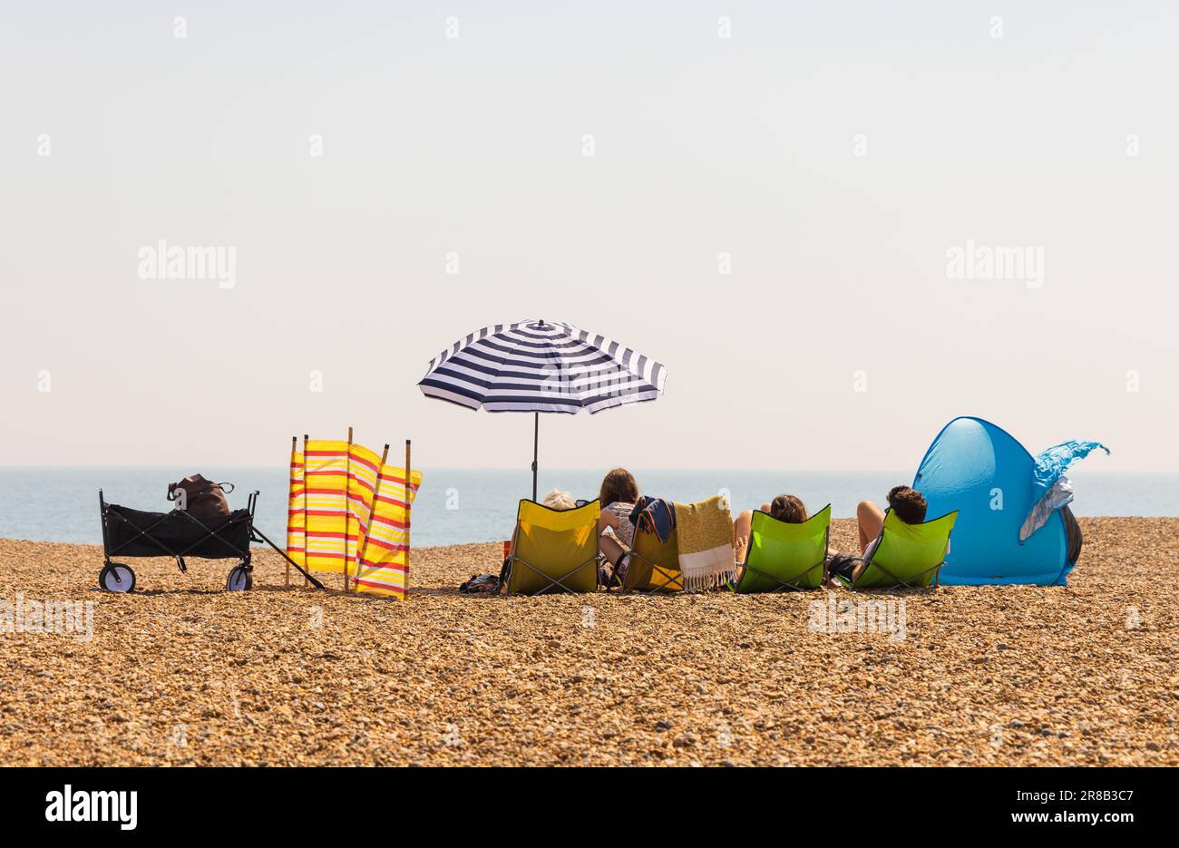 Les touristes se détendent et profitent de la vue sur la mer sur la plage d'Aldeburgh lors d'une journée ensoleillée. Suffolk, Royaume-Uni Banque D'Images