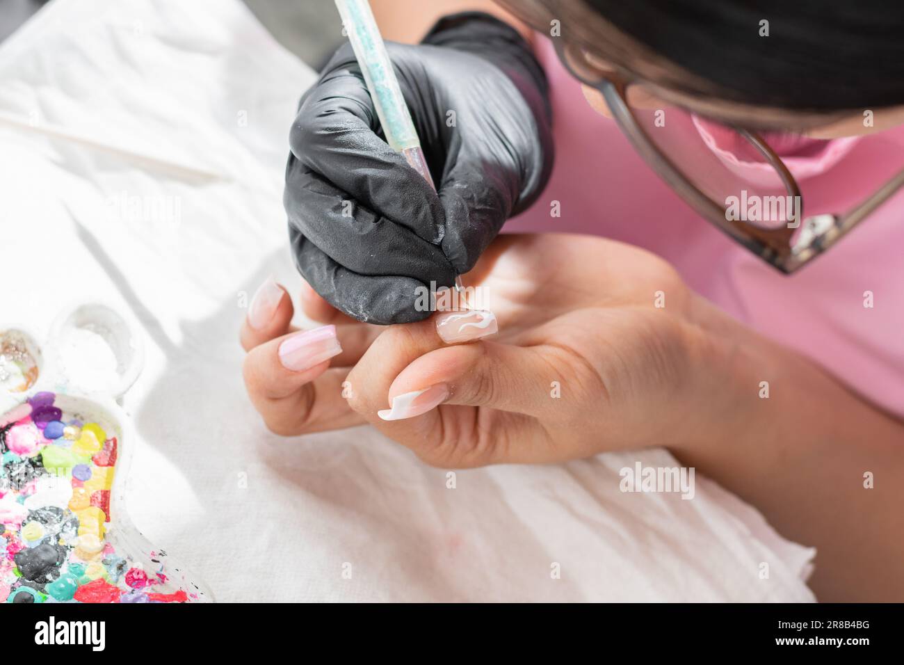 vue de dessus d'une jeune femme décorant soigneusement ses ongles avec une brosse de manucure. Banque D'Images