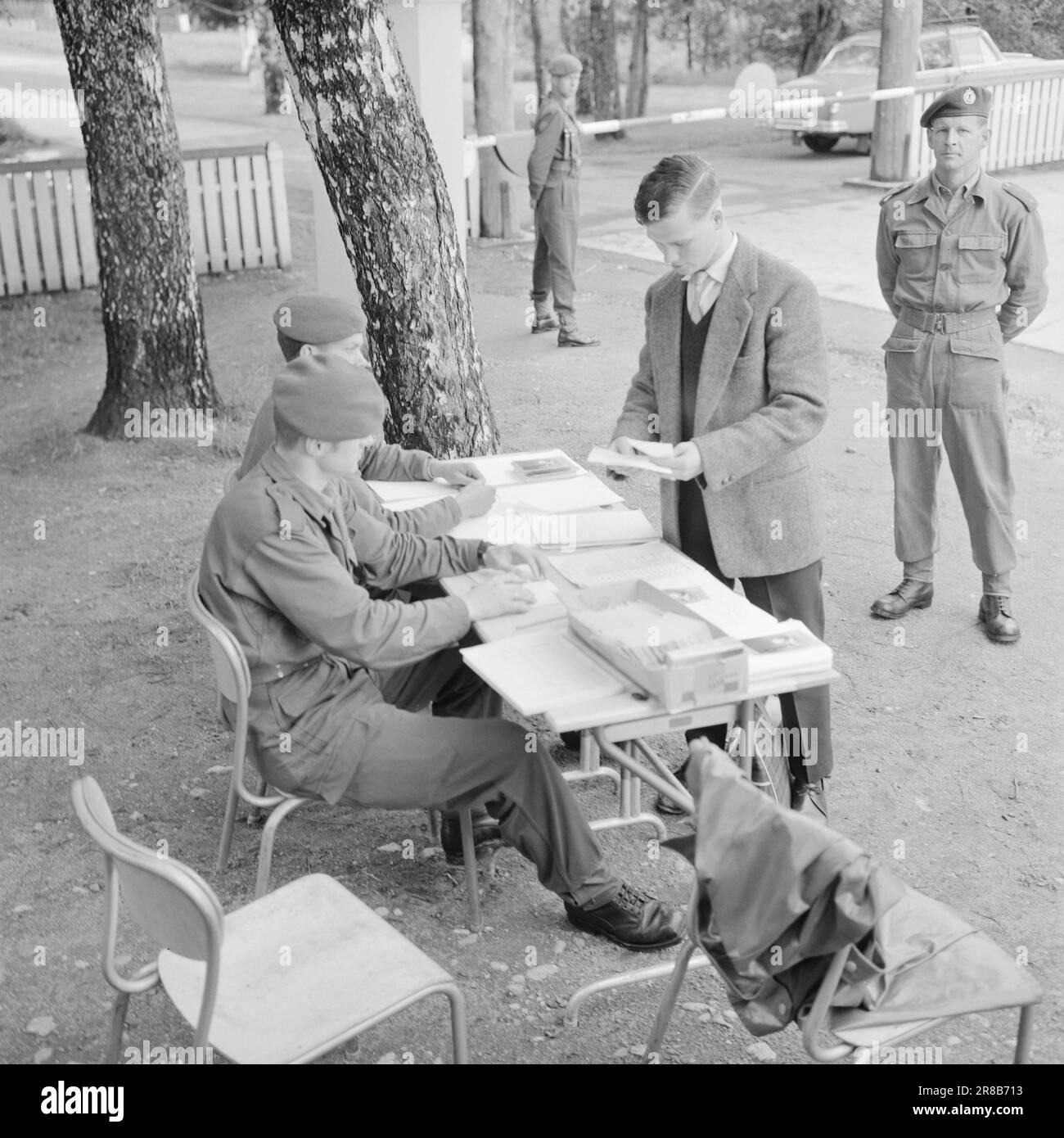 Actuel 32-1-1960: Thore devient une recrue devenir une recrue est une affaire sérieuse. Les sergents, les enseignes, les lieutenants et les capitaines prennent la relève des mères, des pères, des épouses et des fiancees - pendant 16 mois, de longs mois pour un homme de 20 ans. Derrière la barrière Thore Holth se trouve à l'intérieur de la porte du camp. Les papiers sont dans l'ordre et en quelques secondes il est suivi à la caserne par un sergent. « Bienvenue à Lahaugmoen », a déclaré Ensign Thorbjørn Hvattum, qui a montré aux nouveaux arrivants leur chemin dans de nouveaux environnements. Photo: Aage Storløkken / Aktuell / NTB ***PHOTO NON TRAITÉE*** Banque D'Images