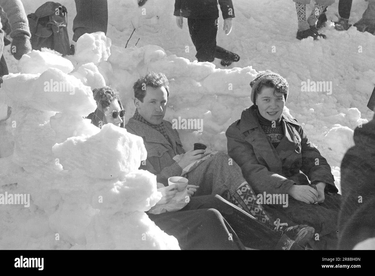 Courant 06-1950: De nouvelles pages à Holmenkollen.cette année le vent était sur le point de souffler l'ensemble de Holmenkollrennet, mais après un report de trois heures il est mort, et le grand festival folklorique qui attire tous, même à ceux qui s'occupent peu pour le sport, est allé de la pile conformément à la réglementation. Voici des photos du photographe Sverre A. Børretzen qui montrent la vie qui s'est déroulée parmi les 90 000 spectateurs avant, pendant et après la course. -Vous aimez les murs de neige qui protègent le vent ces trois soleils et les empers qu'ils ont apporté avec eux. Bien que l'attente ait été longue, il a été très difficile peu Banque D'Images