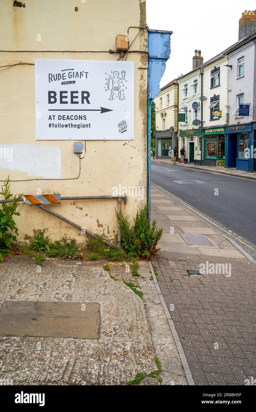 Affiche publicitaire bière géante impolie avec une flèche pointant vers le pub la vendant Banque D'Images