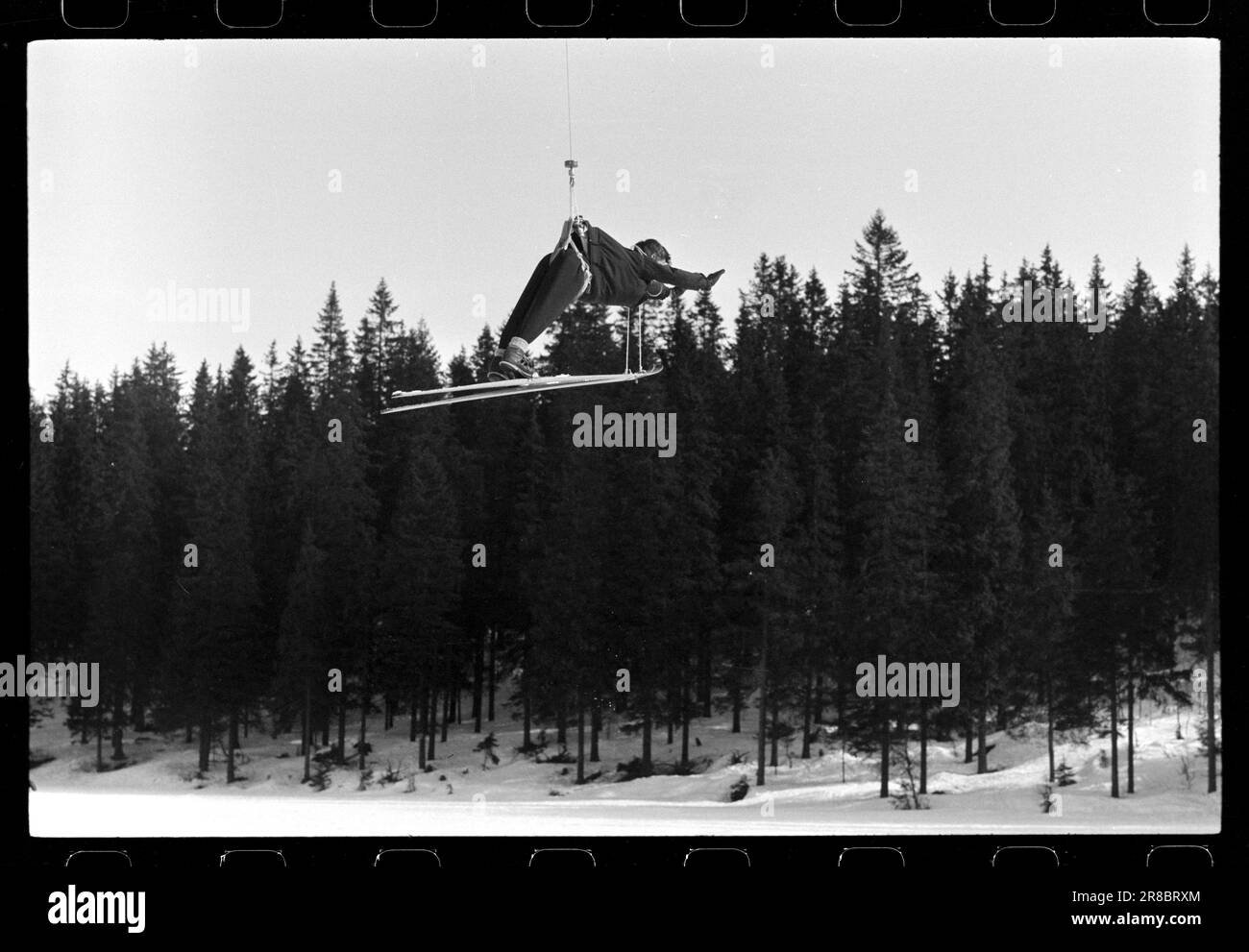 Actuel 18-4-1960: Record de saut de 219,5 mètres l'incroyable s'est produit: Un Norvégien est allé tout et a atteint le record de 219,5 mètres de saut de tous les temps. Le record d'Oberstdorf de 139 mètres a été battu par 80,5 mètres par le photographe d'Aktuell Ivar Aaserud! Nous avons laissé notre employé Ivar Aaserud, qui est un garçon de Kongsberg et qui devrait donc être à l'intérieur avec certaines conditions, accroupi à un hélicoptère, et avec les skis solides de Birger Ruud sur ses jambes, il a été commandé à l'air. Le record de saut a été à son plus haut au-dessus de l'école de ski de Tomm Murstad. Notez le style efficace de Kongsberg. Photo : s Banque D'Images