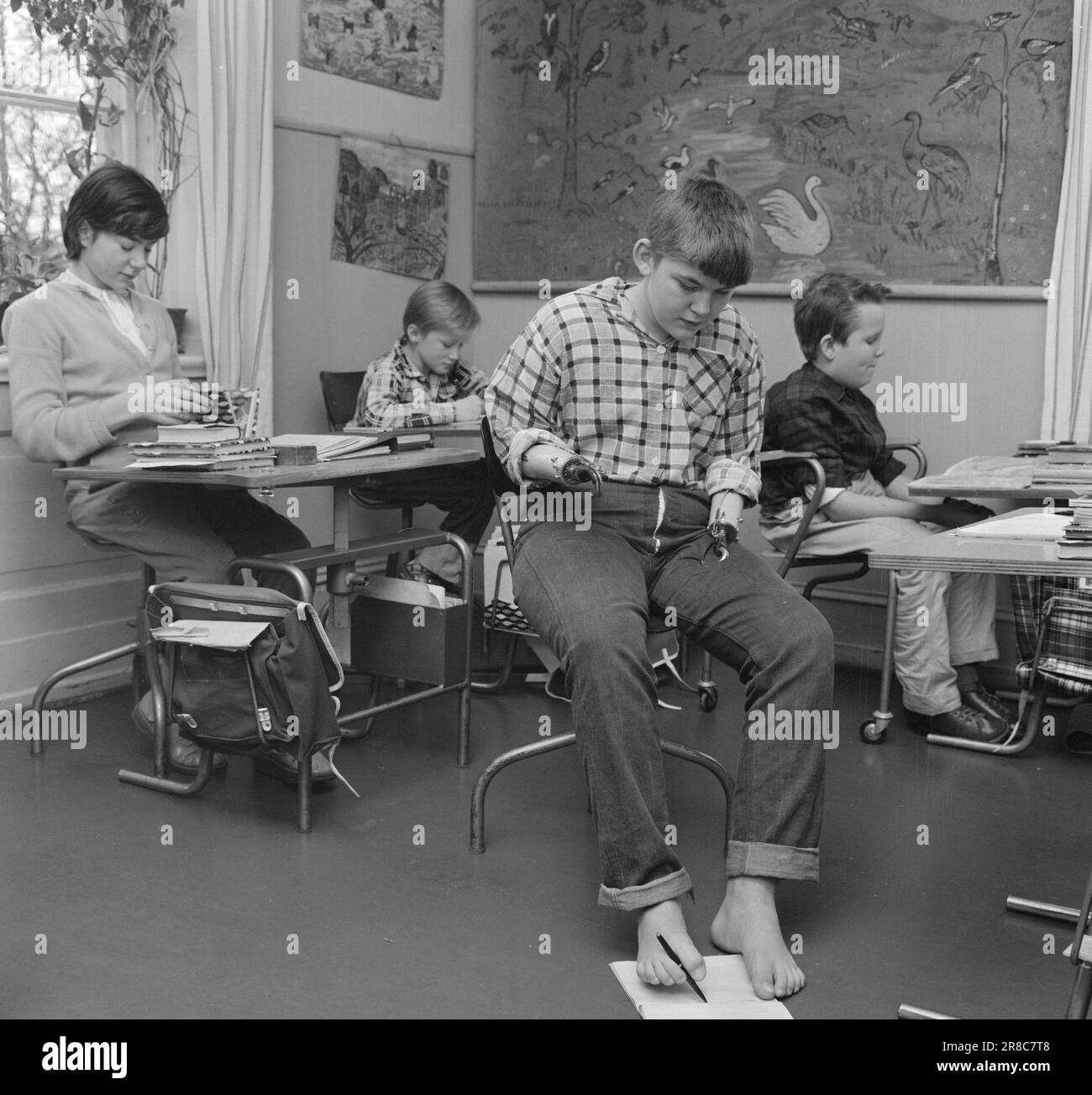 Actuel 50-8-1960: Que dit le tribunal? Un homme de 7 ans du modum a perdu les deux bras en jouant dans un mât haute tension. Aujourd'hui, ce malheureux garçon a 12 ans. Le tribunal lui donnera-t-il 400 000 NOK ? À l'école de Sophies Minde à Oslo, Svein Erik a appris à écrire avec sa prothèse droite. Mais il aime mieux la méthode qu'il s'est enseigné: De conduire le crayon avec ses pieds. Photo: Aage Storløkken / Aktuell / NTB ***PHOTO NON TRAITÉE*** Banque D'Images