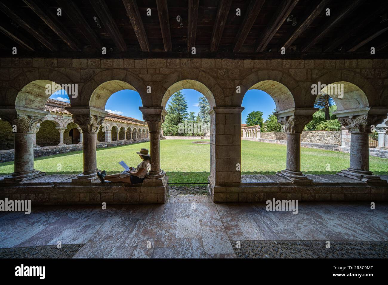 Une femme qui lit dans le cloître de l'abbaye Saint-Michel de Cuxa, France Banque D'Images