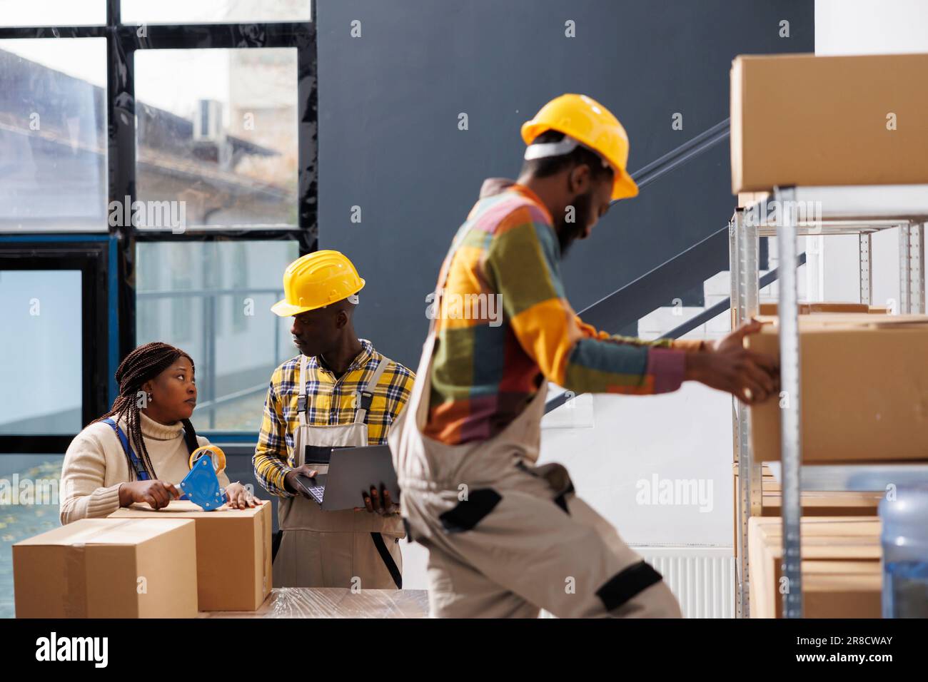 Les employés de l'entrepôt emballant l'emballage de la commande client avec un distributeur d'adhésif. Les employés de l'entrepôt utilisent du ruban adhésif pour fermer les boîtes en carton et discuter du bon de cueillette des commandes Banque D'Images
