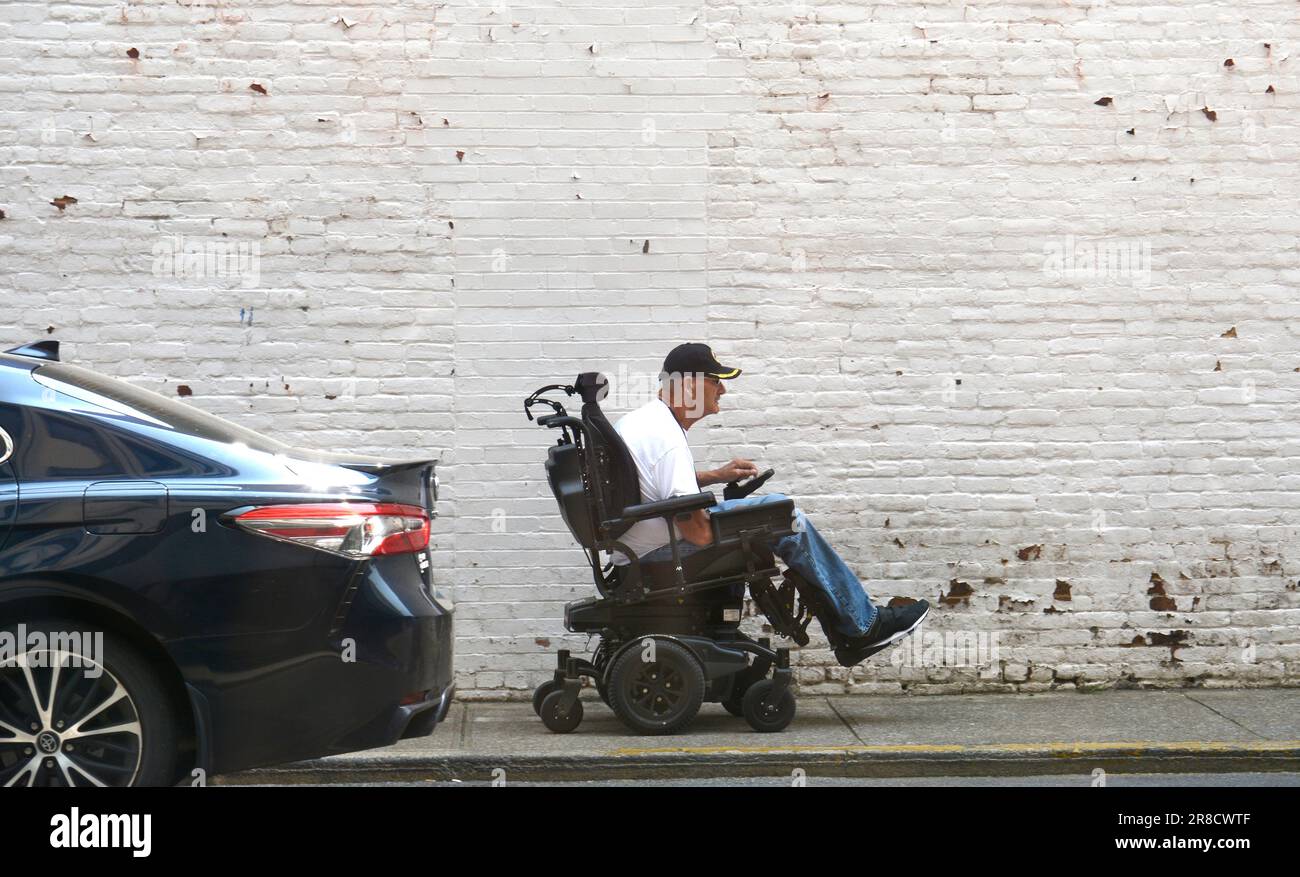 Un homme roule en fauteuil roulant motorisé, ou en fauteuil roulant motorisé, le long d'un trottoir à Bristol, en Virginie. Banque D'Images