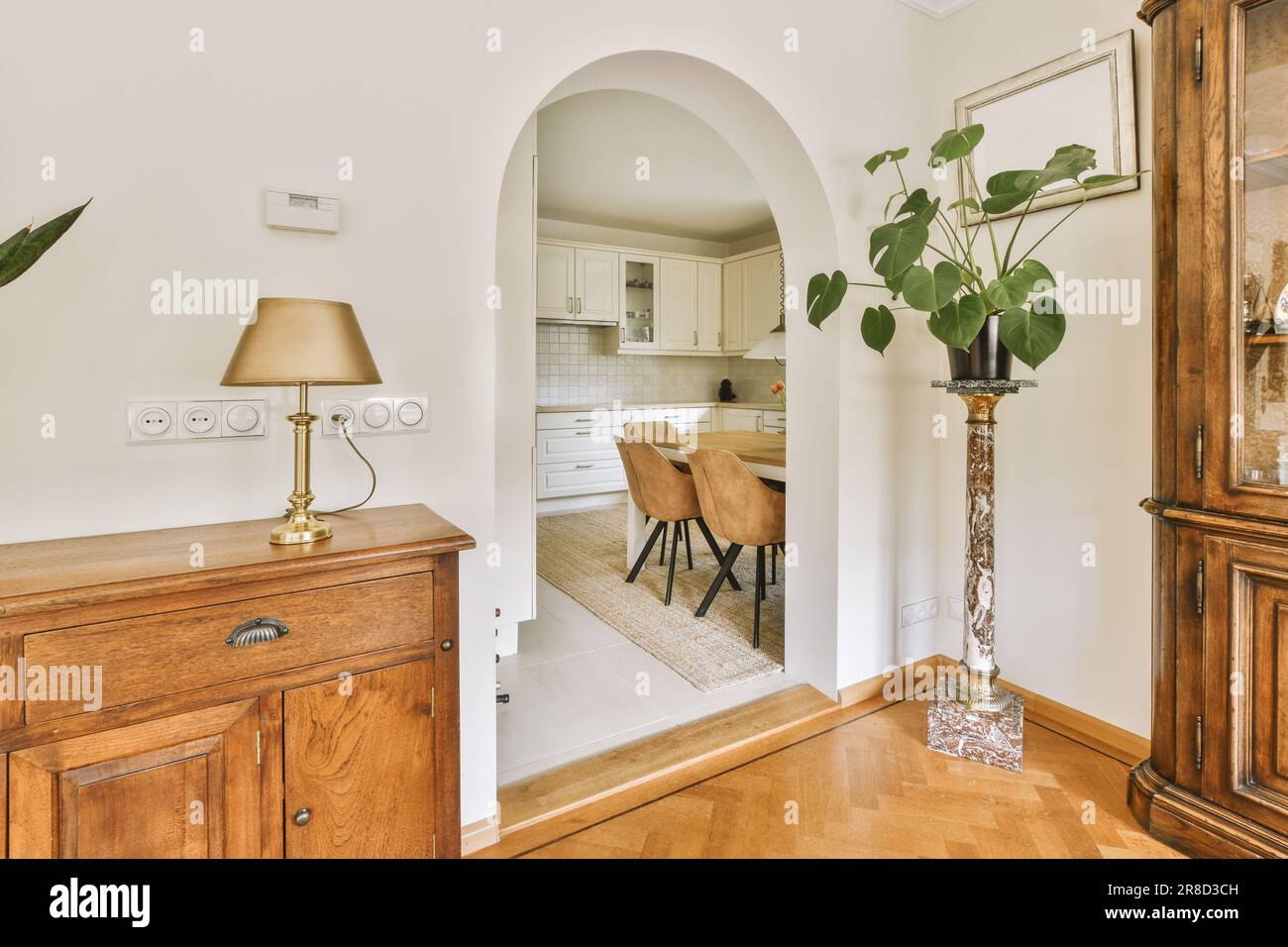 un salon avec une table à manger et une arcade menant à la cuisine dans la porte est ouvert sur le côté droit Banque D'Images