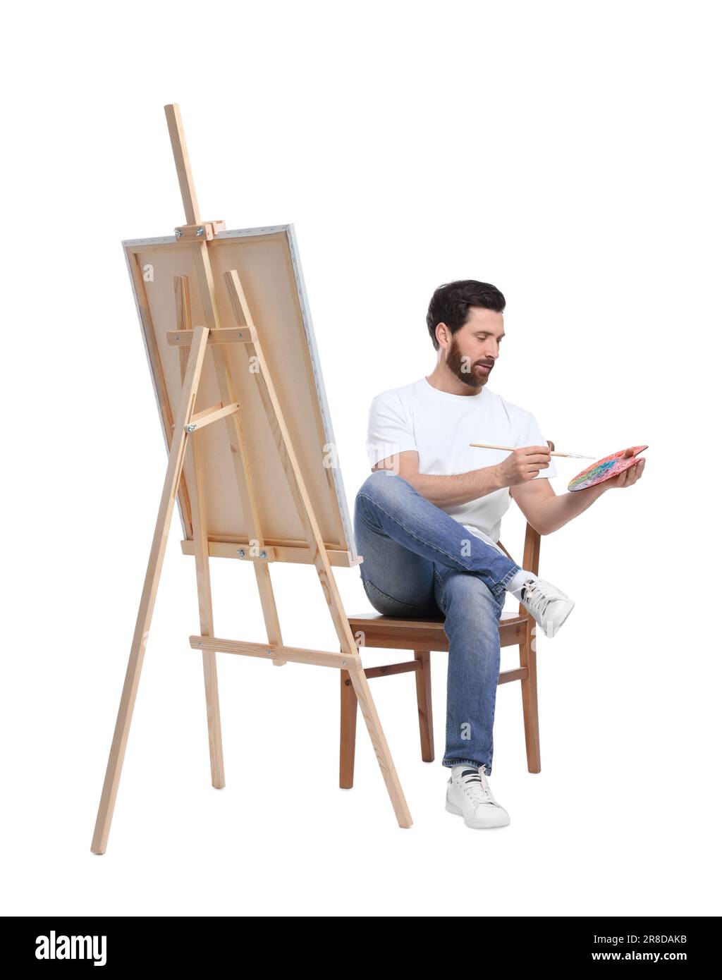 Homme avec peinture au pinceau sur fond blanc. Utilisation du chevalet pour tenir la toile Banque D'Images