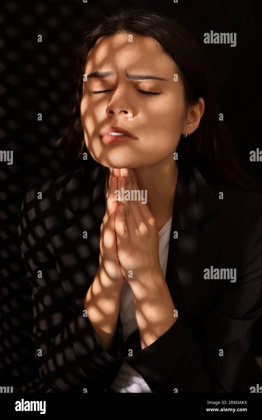 Femme priant à Dieu pendant la confession en cabine Banque D'Images