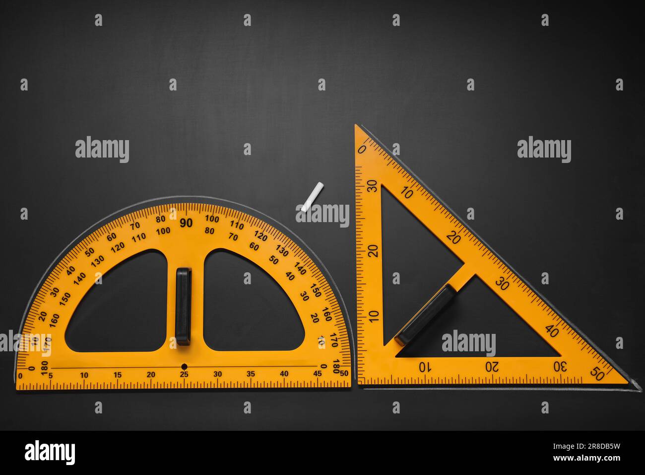 Rapporteur, règle triangulaire et craie sur table noire, plat. Espace pour le texte Banque D'Images