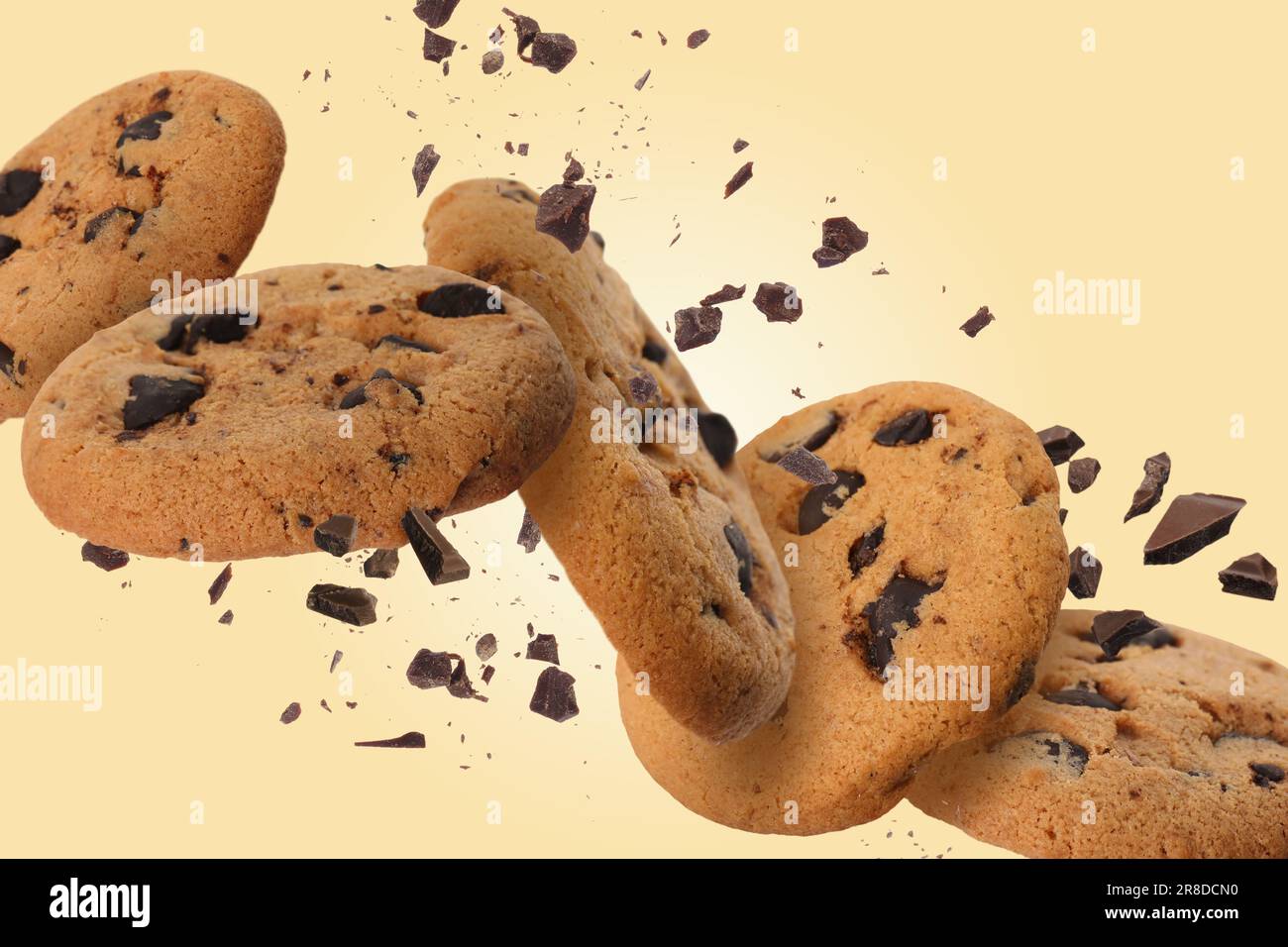 Délicieux biscuits aux pépites de chocolat tombant sur fond d'or pâle Banque D'Images
