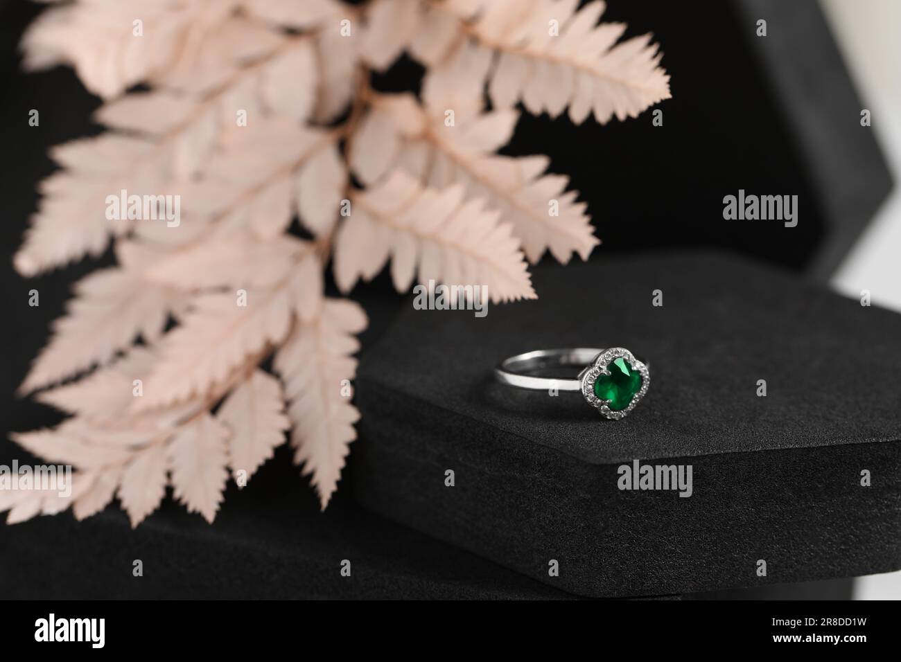 Belle bague avec pierre précieuse verte sur podium noir, gros plan. Bijoux de luxe Banque D'Images