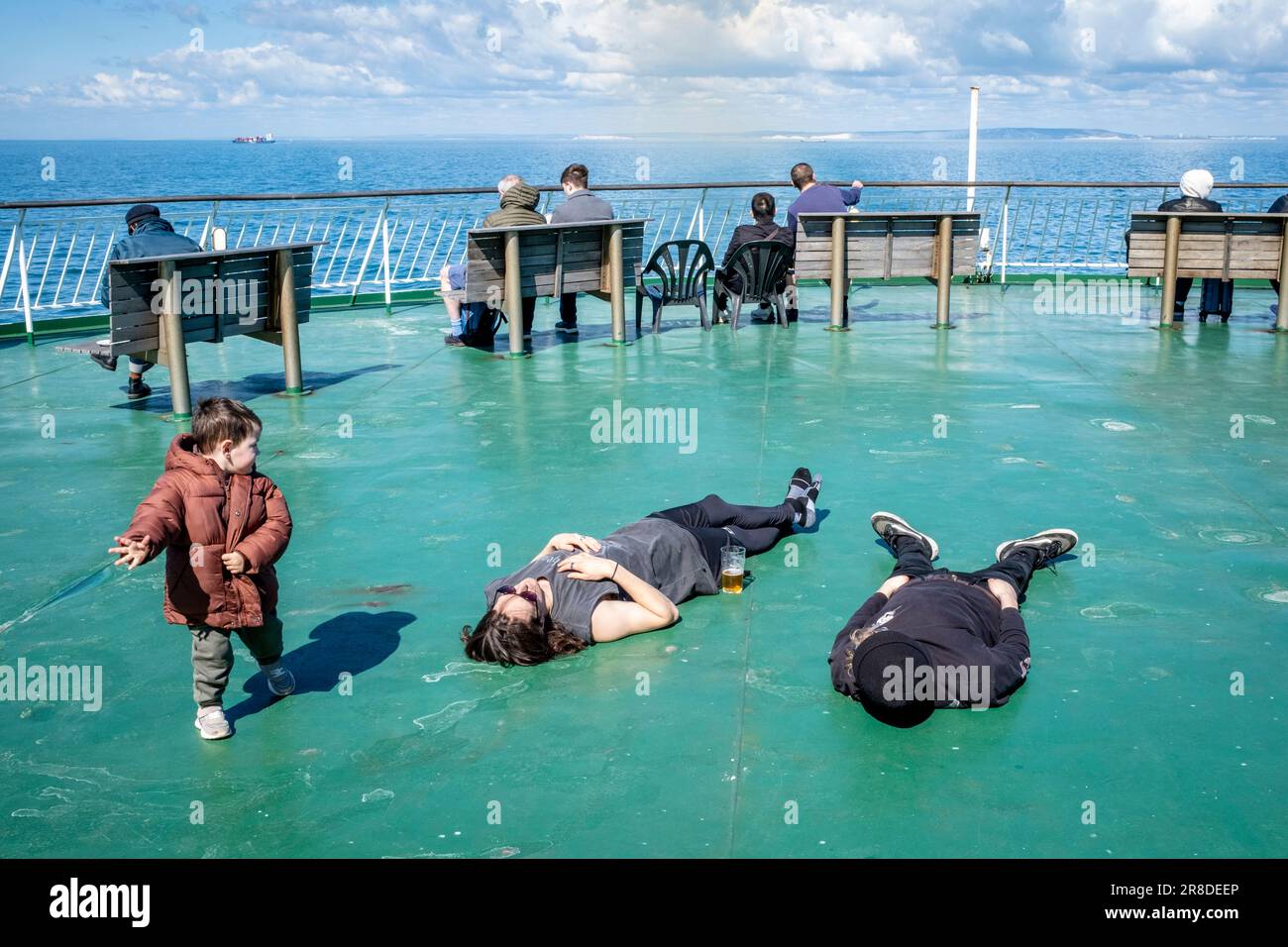 Un petit enfant regarde deux passagers dormant à bord D'Un ferry DFDS Cross Channel au large de la côte Sussex, au Royaume-Uni. Banque D'Images