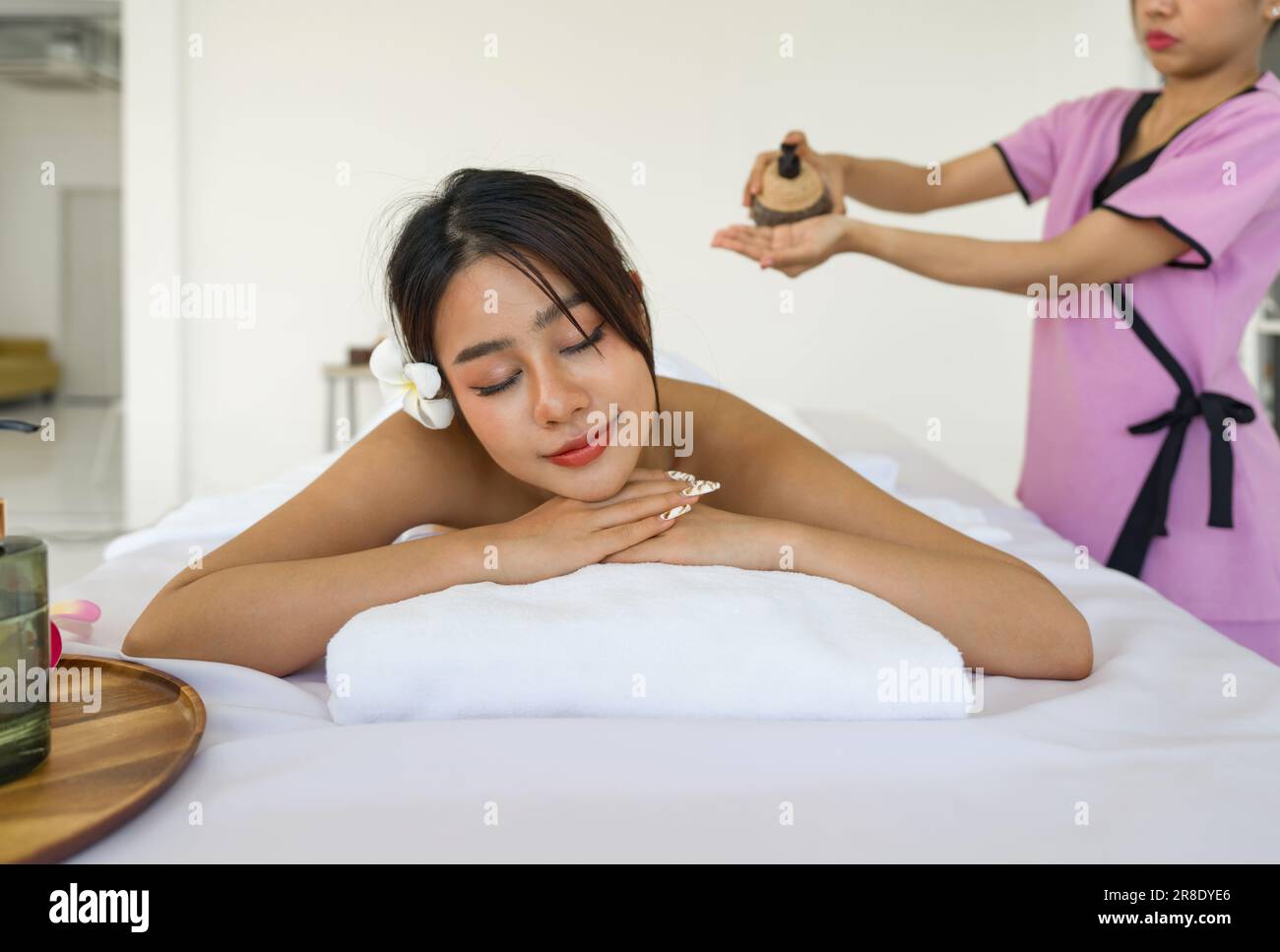 Une jeune femme asiatique se fait masser au spa. Allongé sur une table de massage, relaxant avec les yeux fermés. Spa soins thermaux aromathérapie pour le corps de beauté. Banque D'Images