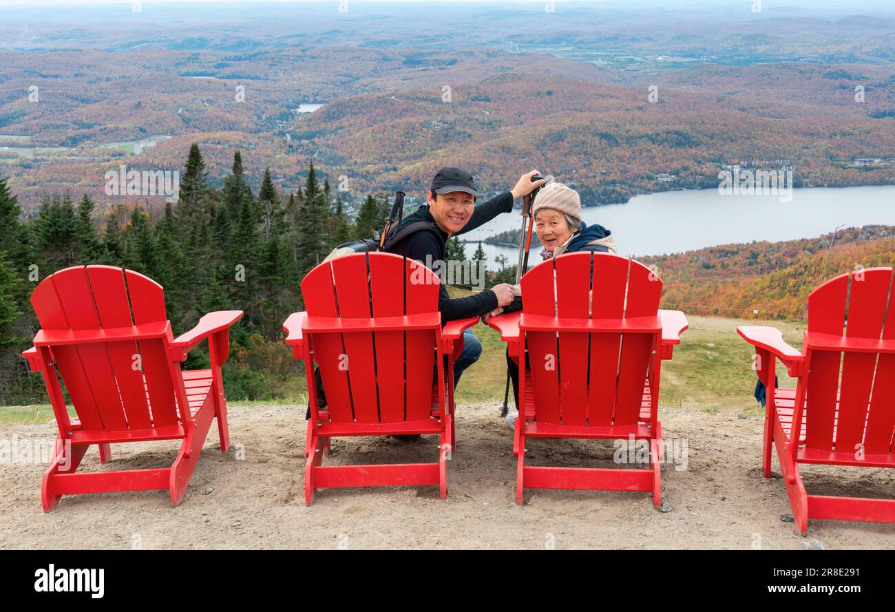Femme et fils chinois senior assis sur des chaises rouges et posant pour des photos au sommet du Mont Tremblant. Québec. Canada. Banque D'Images