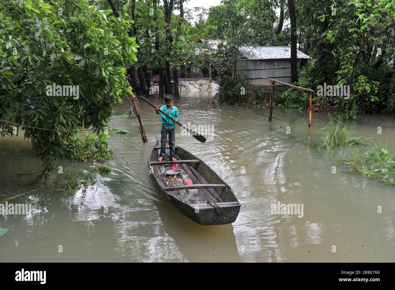 En raison des pluies continues et des pentes de colline, le niveau d'eau des rivières et des cours d'eau augmente et l'eau entre dans la localité. Il y a un risque d'inondation. Un petit garçon utilise un bateau pour le transport près de sa maison submergée. Nandir Gao Union de Goainghat Upazila. Sylhet, Bangladesh. Banque D'Images