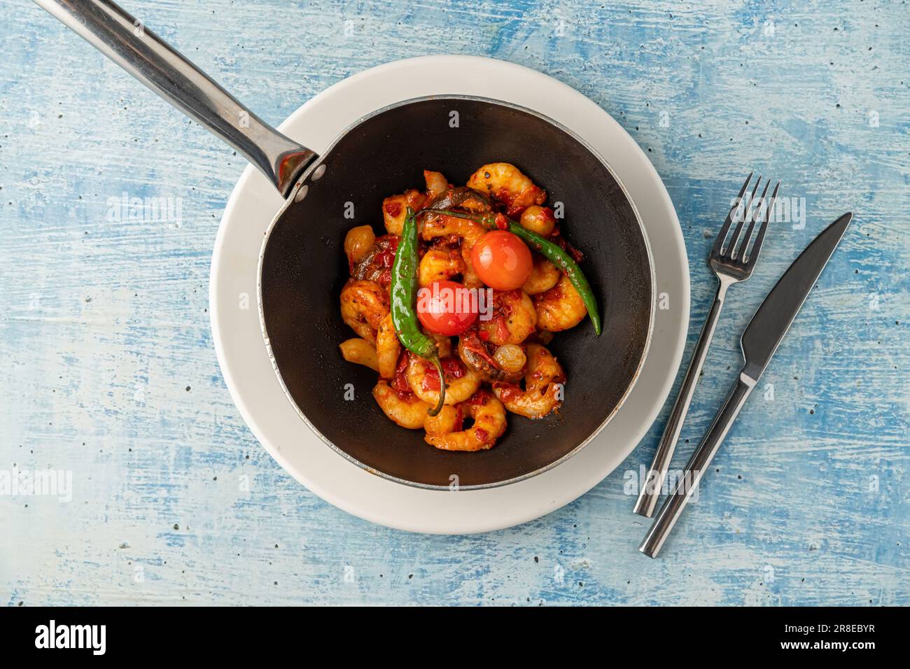 Cocotte de crevettes avec tomates, ail et poivrons dans un wok noir Banque D'Images