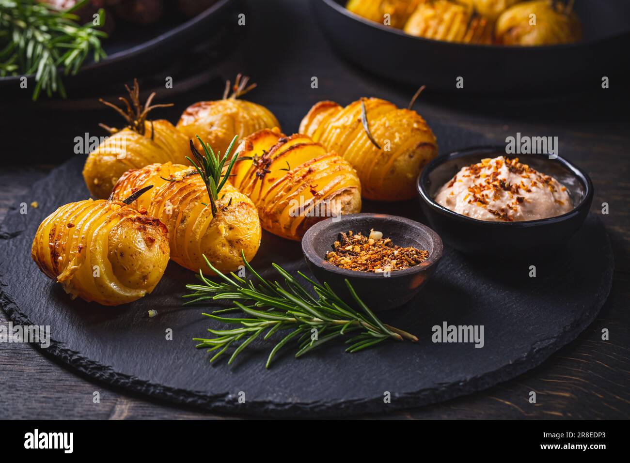 Pommes de terre Hasselback (ventilateurs de pommes de terre) avec des herbes supplémentaires, des épices et une sauce à la féta fouettée Banque D'Images