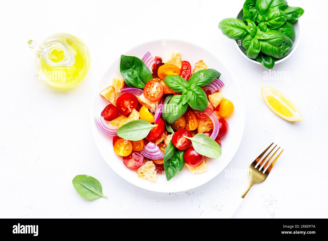 Salade de légumes d'été panzanella avec pain rassis, tomates colorées, oignon rouge, huile d'olive, sel et basilic vert, fond de table blanc, vue du dessus Banque D'Images