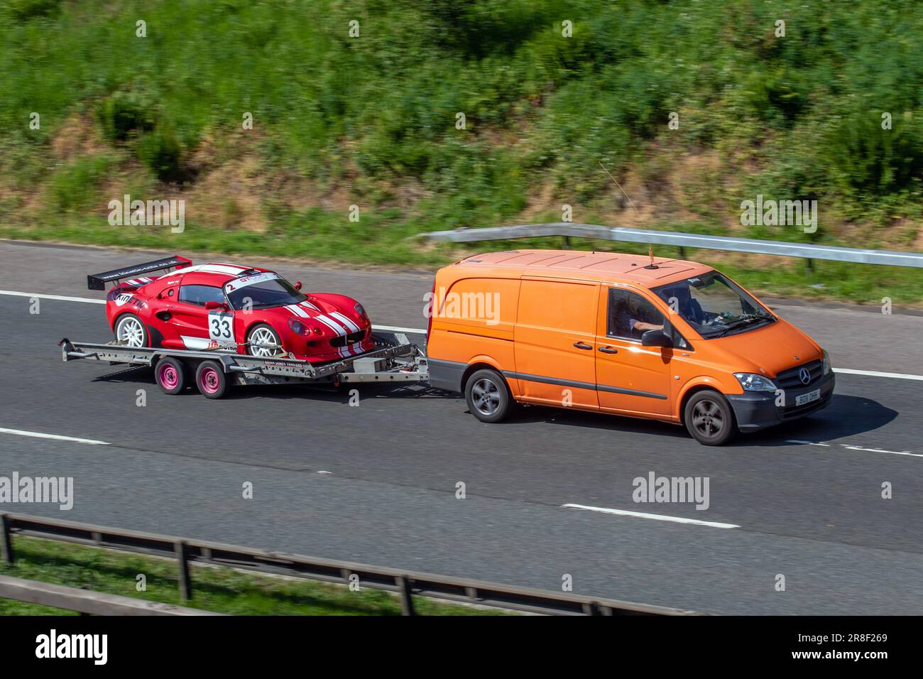 Lotus Motorsport Elise - Honda Supercharged Racing, Red White Rally car Lotus Elise No.33 sur une remorque remorquée par Orange Mercedes Benz Sprinter van, sur l'autoroute M6, Royaume-Uni Banque D'Images