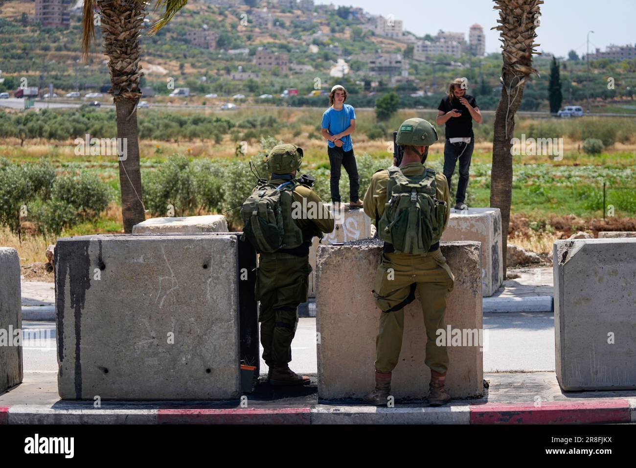 Israeli soldiers stop Jewish settlers from entering the Palestinian West Bank town of Turmus Ayya, Wednesday, June 21, 2023. Israeli settlers set fire to Palestinian cars after four Israelis were killed by Palestinian gunmen in the northern West Bank on Tuesday. (AP Photo/Ohad Zwigenberg) Banque D'Images