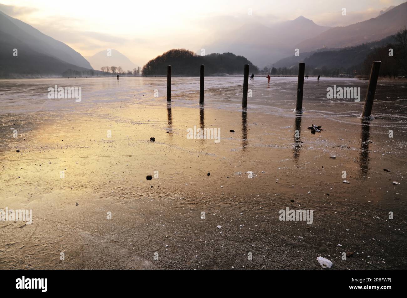 Glace sur un lac au coucher du soleil et patinage sur glace en Italie Banque D'Images