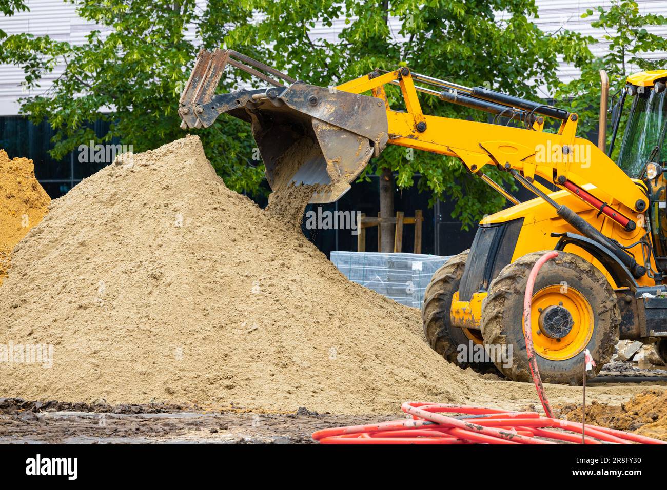 la pelle jaune fait des travaux de terrassement dans la rue. la pelle hydraulique jaune creuse le sol Banque D'Images