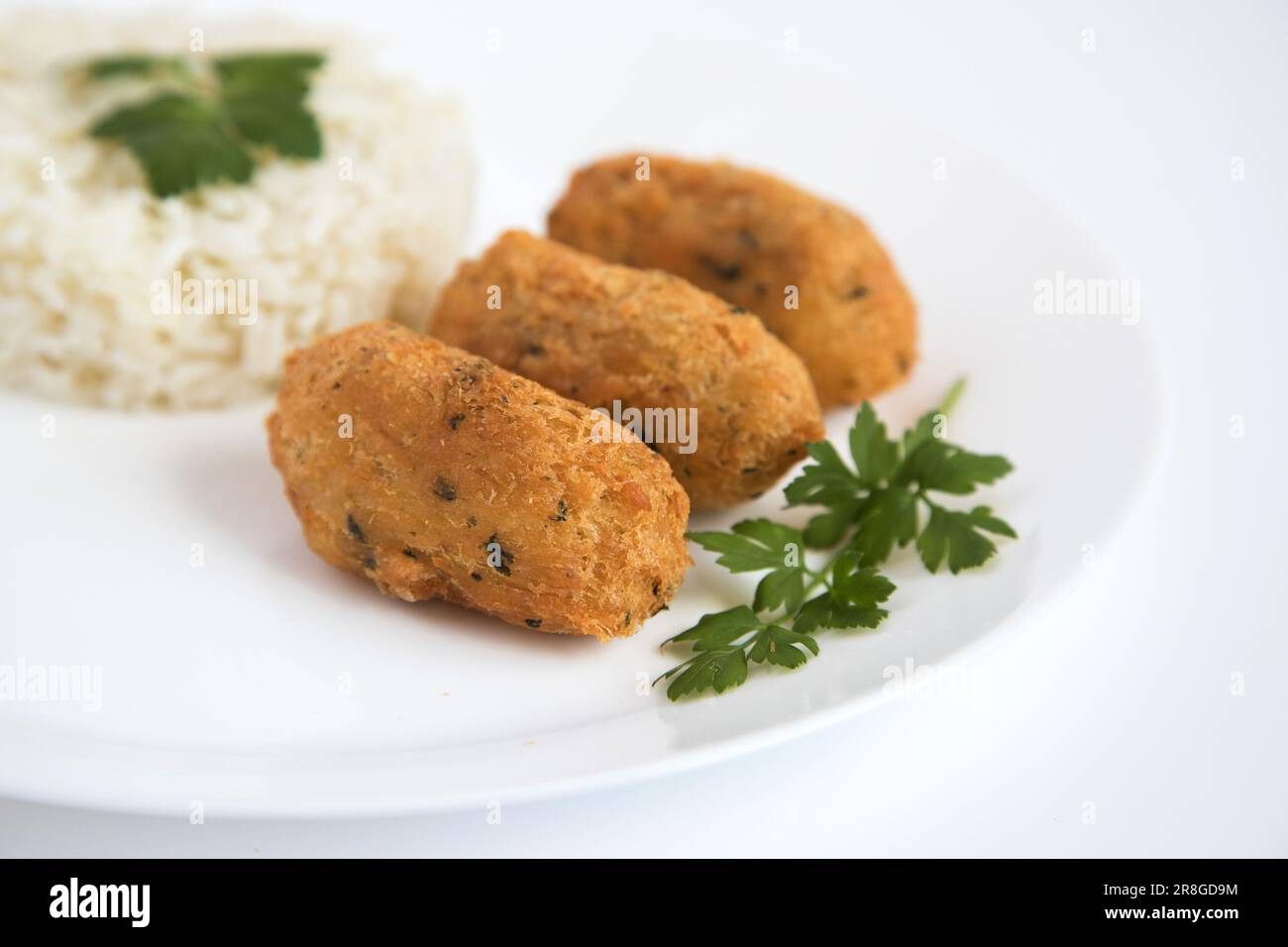 Boulettes de morue, ou « bolinhos de bacallahau », très célèbre dans la gastronomie portugaise. Assiette de pâtisseries à la morue servies avec du riz blanc. Banque D'Images