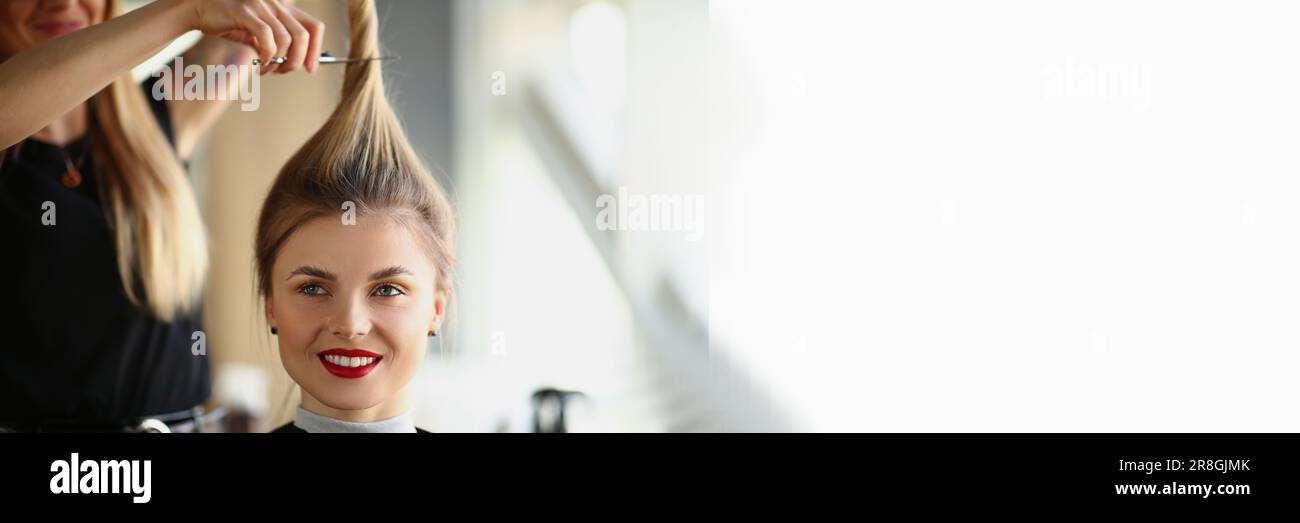 Les mains du coiffeur coupent la queue blonde de près Banque D'Images