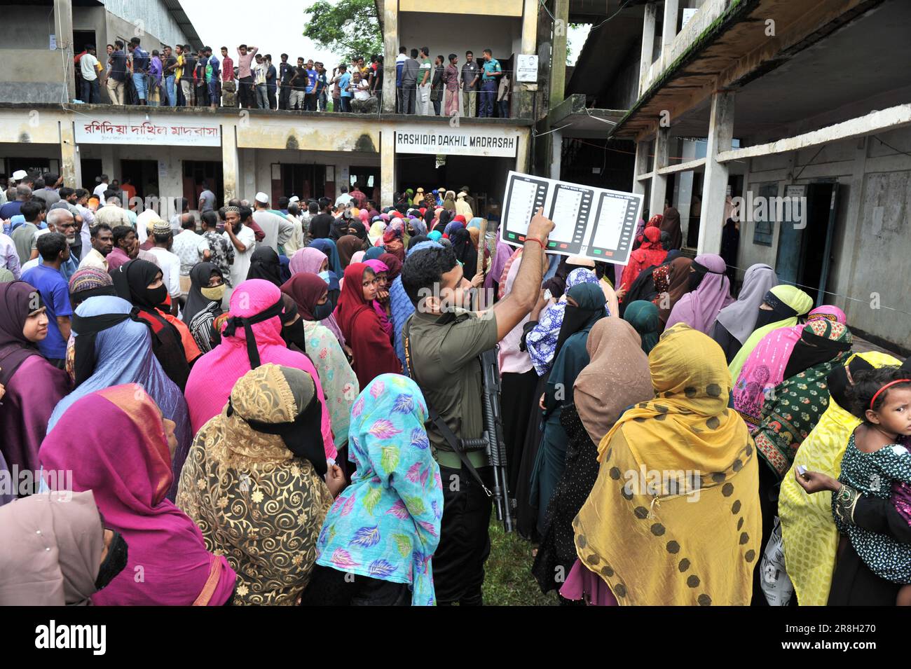 Sylhet, Bangladesh. 21st juin 2023. Des milliers d'électeurs sont venus au bureau de vote de Rashidiya Dakhil Madrasa, numéro 38, qui a été récemment ajouté à Sylhet City Corporation. Les gens ont fait un coup de pied spontané dans les bureaux de vote, mais la lenteur des EVM les a déçus. Pendant ce temps, les membres d'Ansar sont debout et montrent comment voter aux machines EVM. Banque D'Images