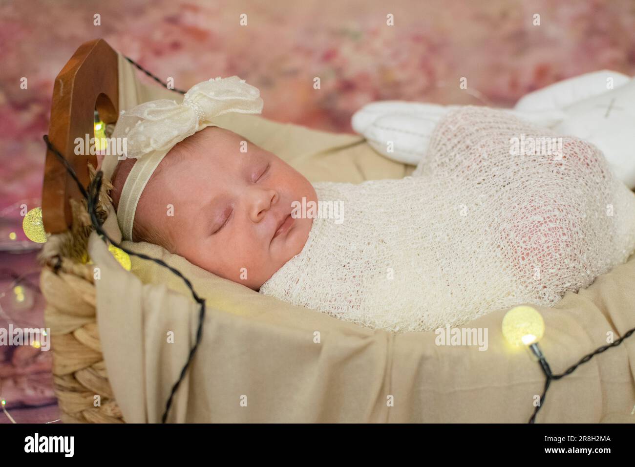 Bébé jeune fille de race blanche en bonne santé dormant enveloppé dans une selle et un arc. Banque D'Images